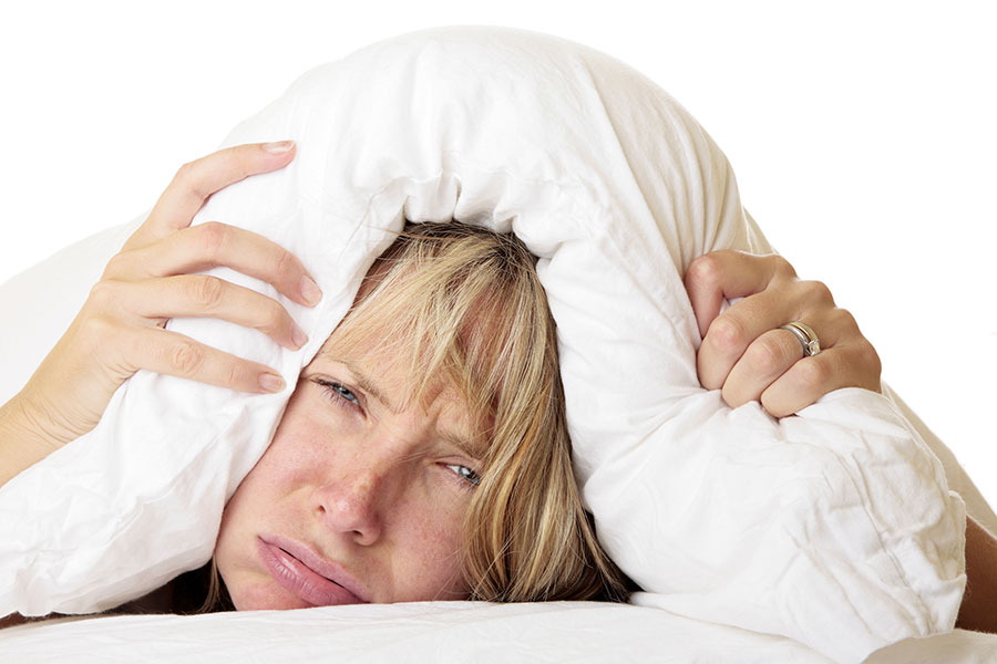 woman with head under pillow cannot sleep insomnia