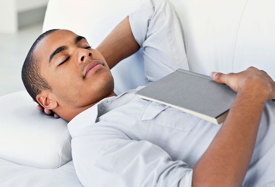 Young african-american man sleeping on a sofa with his hand behind his head