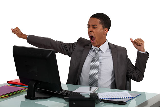 black business man yawning in front of his computer monitor